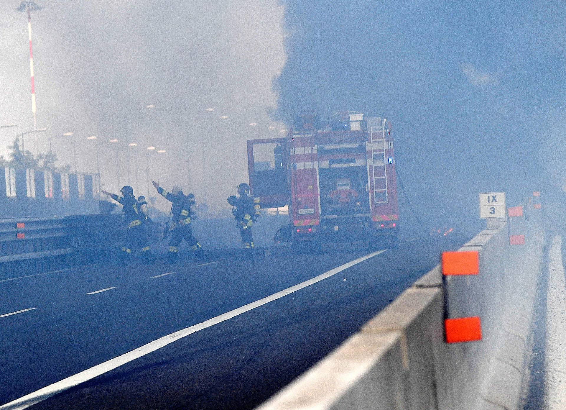 Firefighters work on the motorway after an accident caused a large explosion and fire at Borgo Panigale, on the outskirts of Bologna