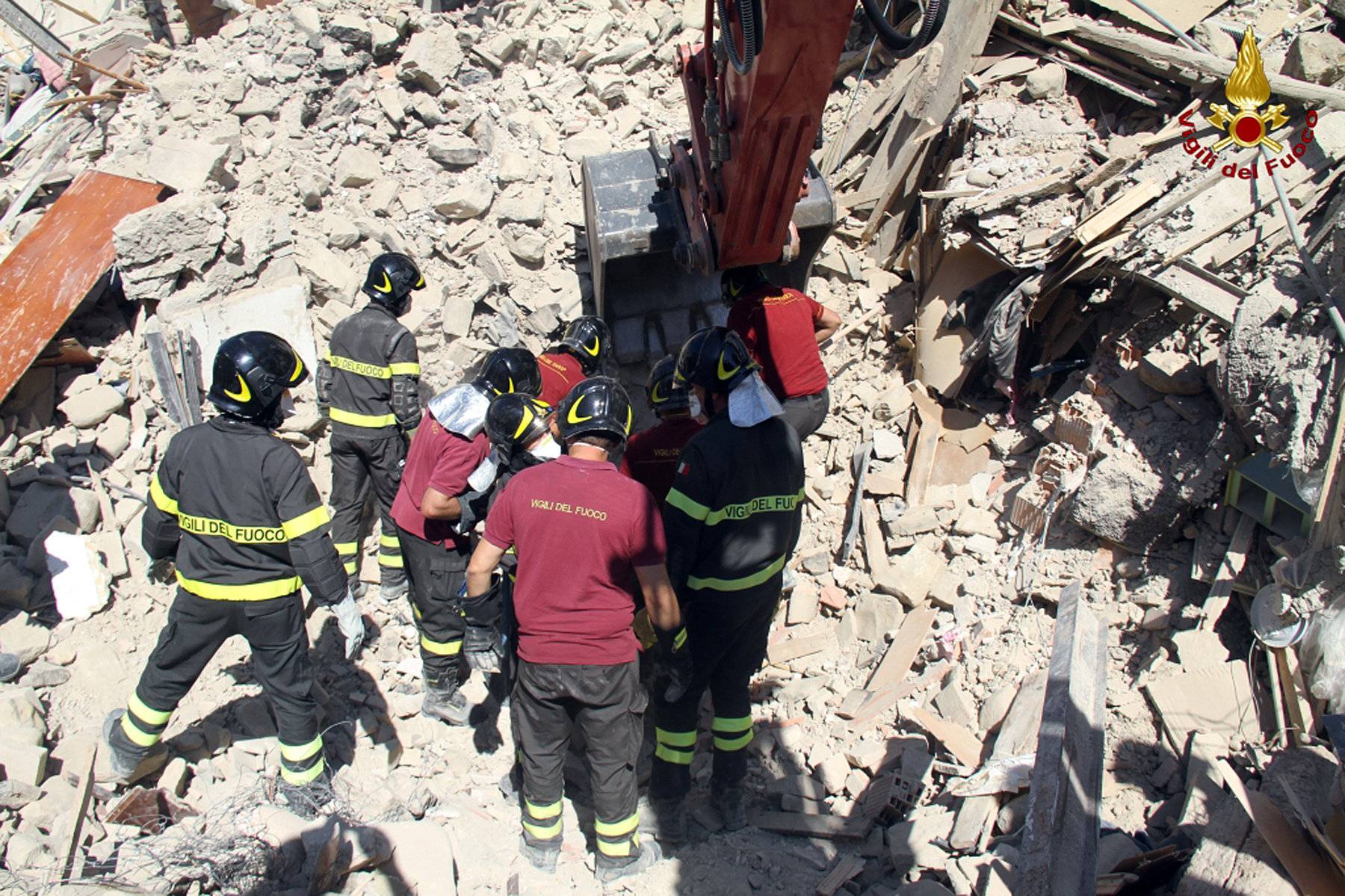 Rescuers work at a collapsed house following an earthquake in Amatrice