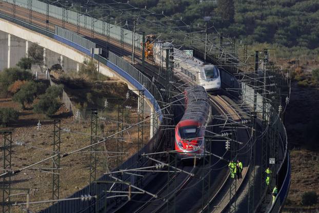 Workers check the railway next to an AVE high-speed train slightly derailed after heavy rains and floods in Alora
