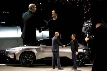 Nick Sampson (L), senior vice president of product R&D and engineering at Faraday Future, shakes hands with YT Jia (L), founder and CEO of LeEco, in front of a Faraday Future FF 91 electric car during an unveiling event in Las Vegas