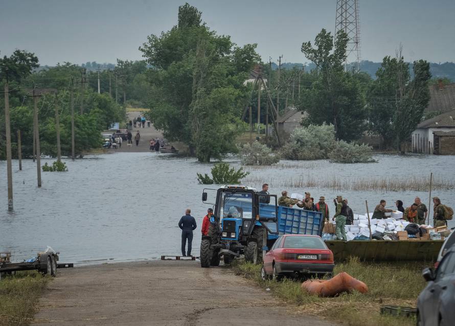Ukrainian servicemen unload humanitarian aid for local residents after the Nova Kakhovka dam breached, in the flooded village of Afanasiivka