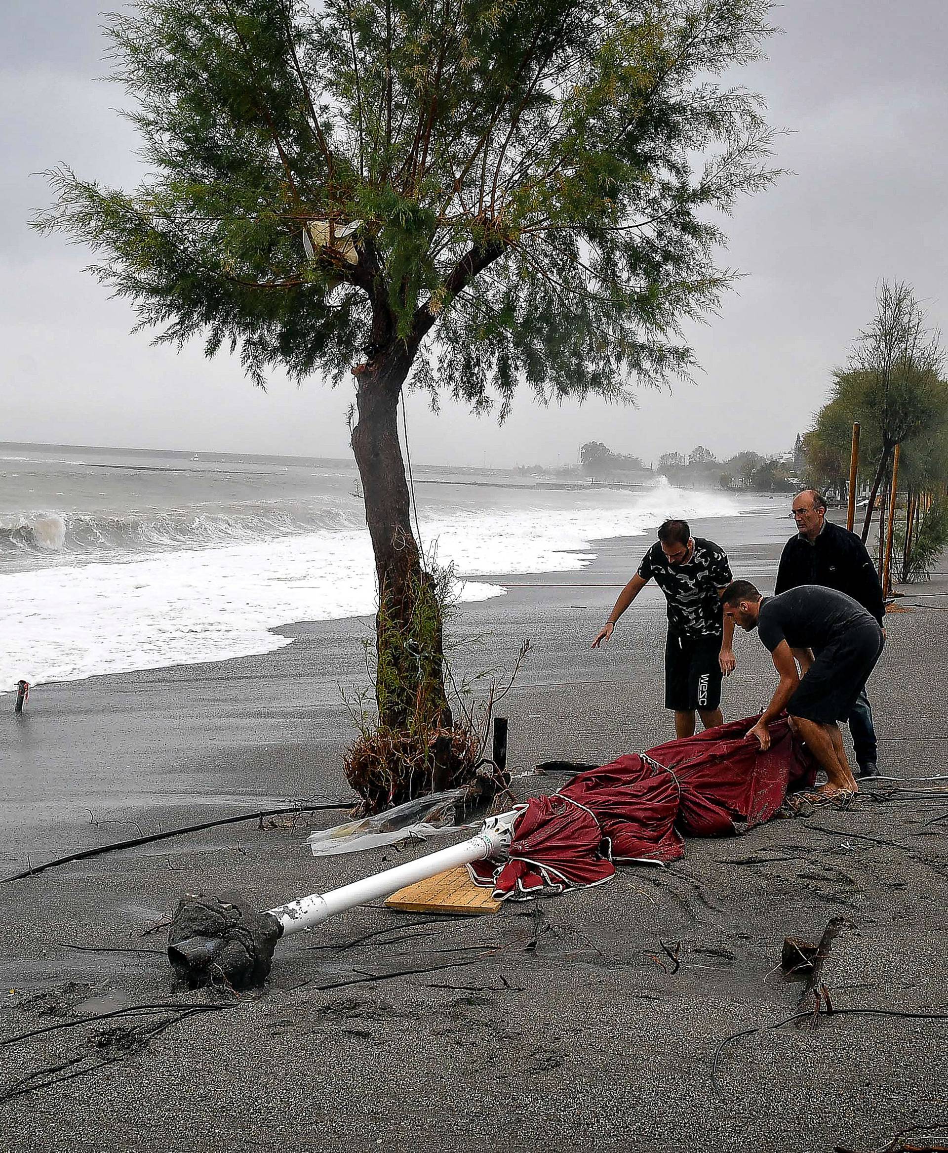 People collect an umbrella from the beach following a cyclone in Kalamata