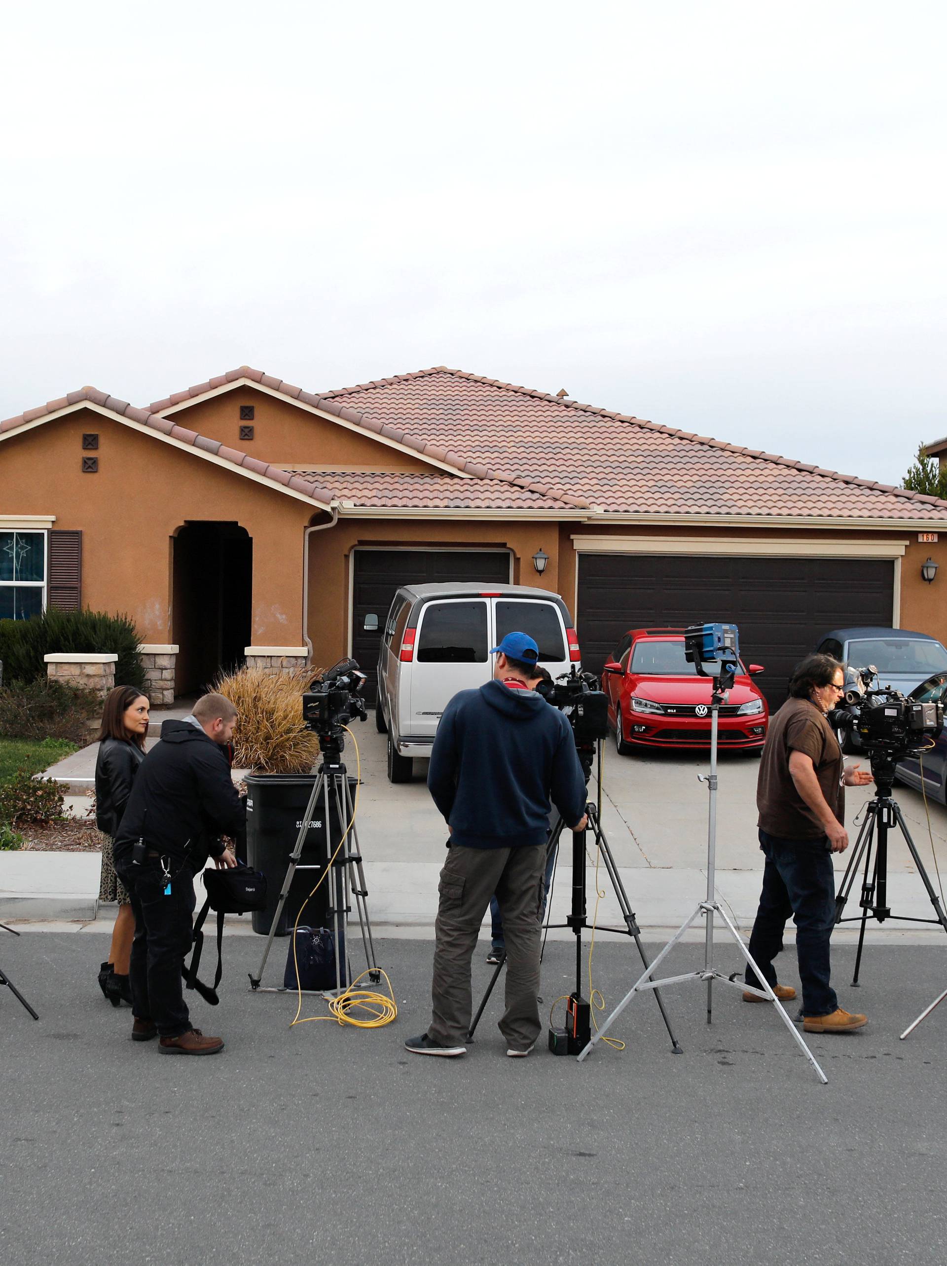 Members of the news media stand outside the home of the Turpins in Perris