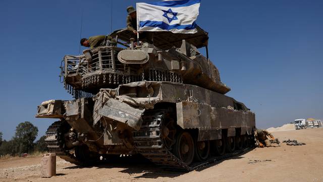 Israeli soldiers mount a flag on a military vehicle near the Israel-Gaza border