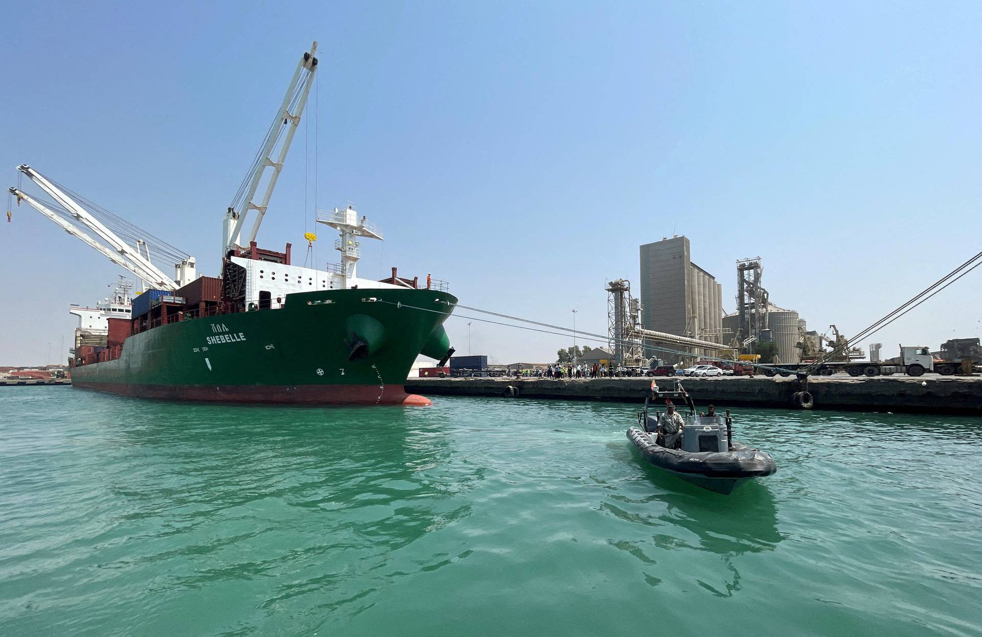 FILE PHOTO: Coastguard boat sails past a commercial container ship docked at the Houthi-held Red Sea port of Hodeidah