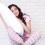 Beautiful girl with pillow sitting on white bed