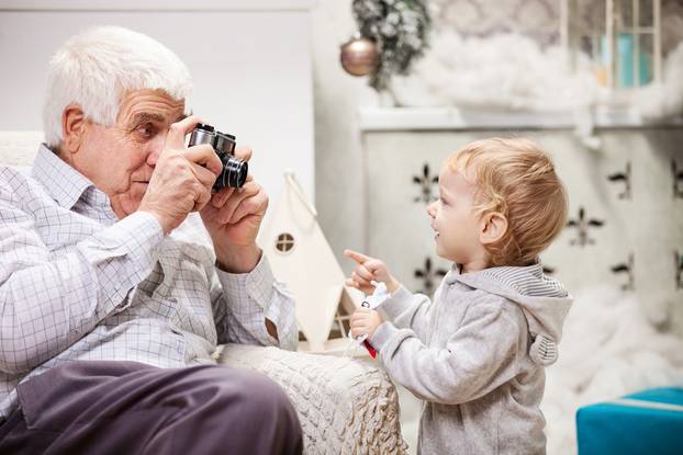 Senior,Man,Taking,Photo,Of,His,Toddler,Grandson,At,Christmas