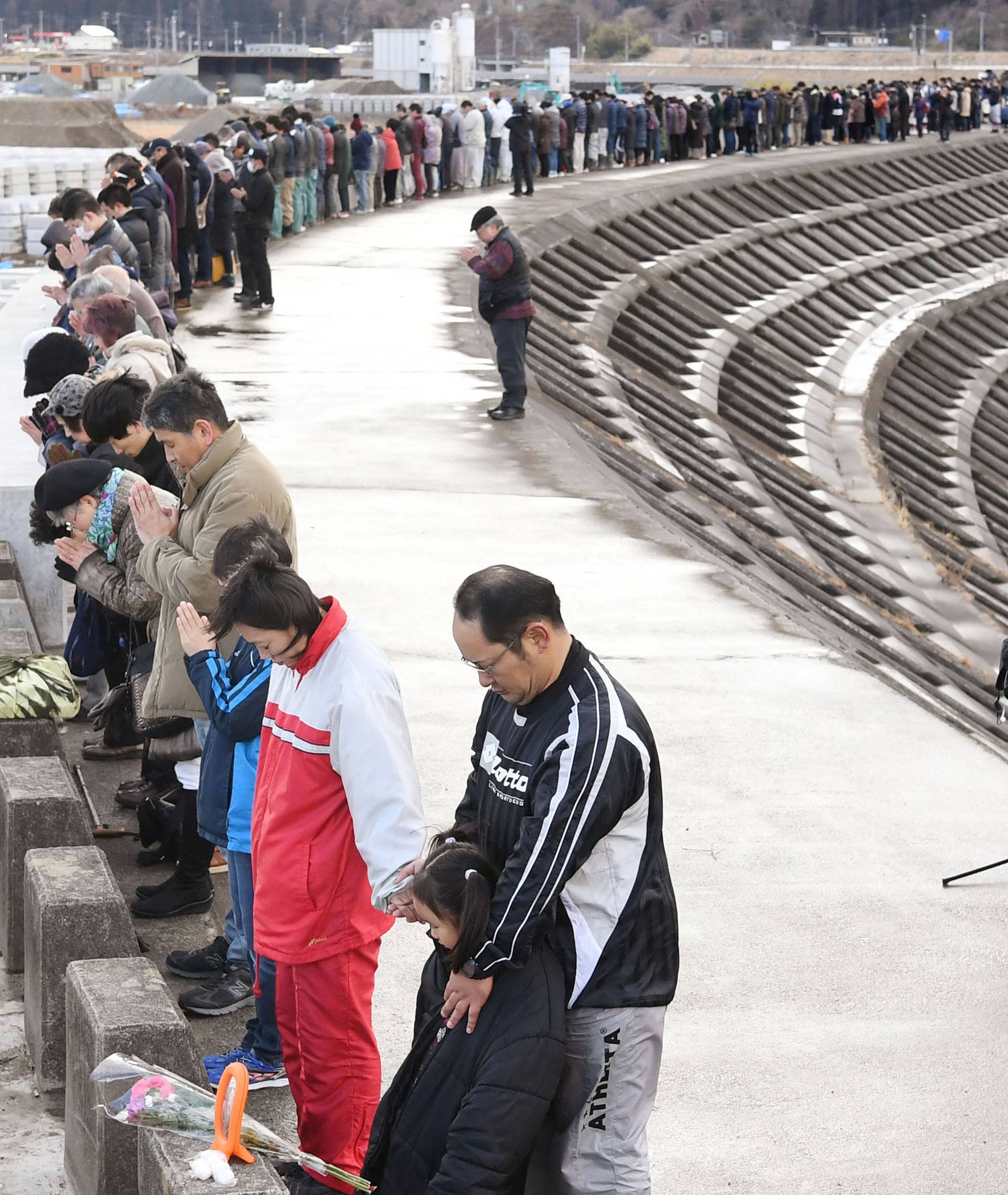 People observe a moment of silence atop of a seawall at Taro district in Miyako, Japan