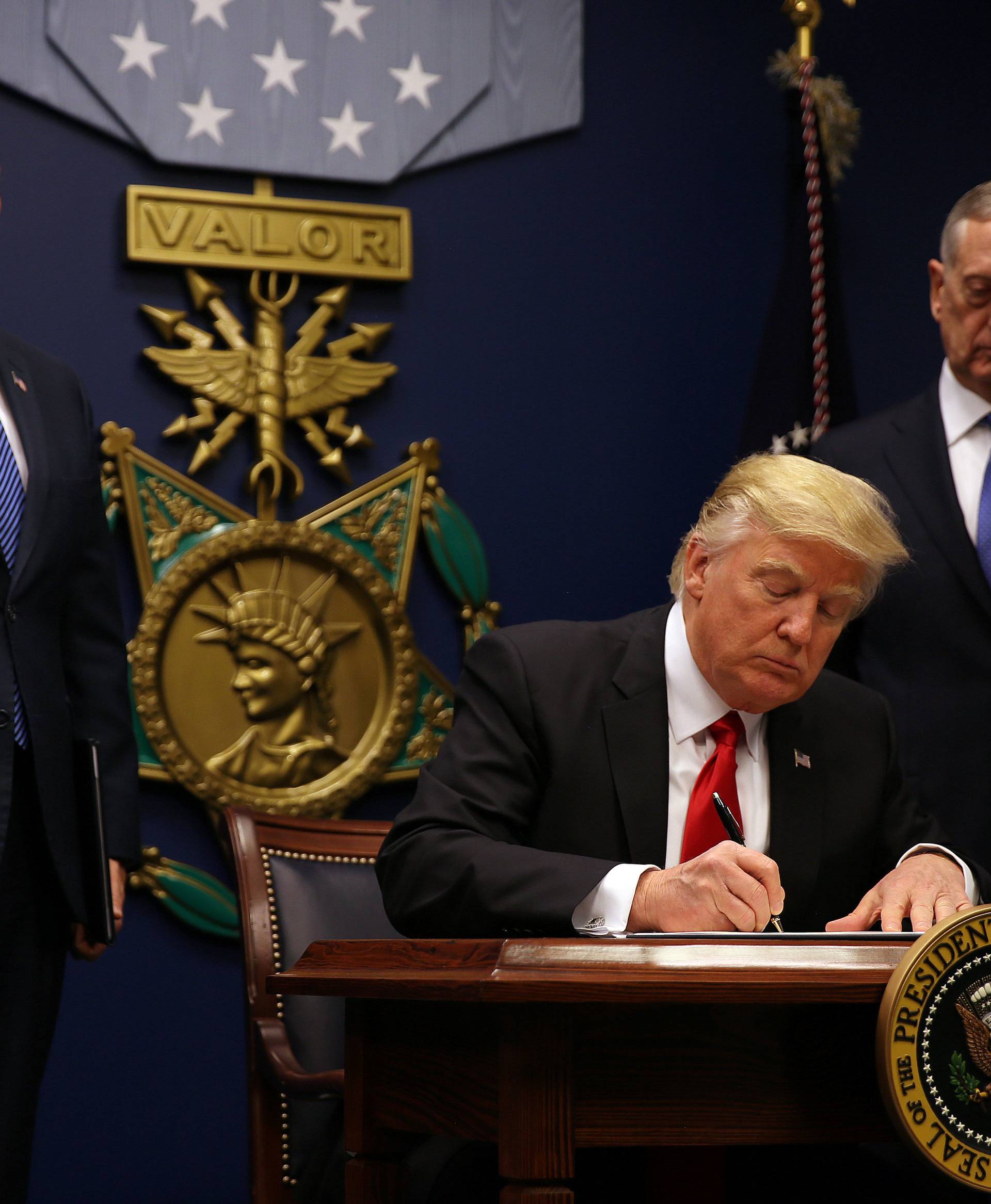 U.S. President Donald Trump signs an executive order he said would impose tighter vetting to prevent foreign terrorists from entering the United States at the Pentagon in Washington