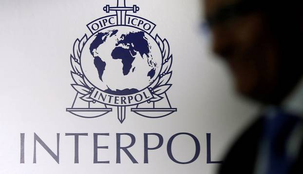 FILE PHOTO: A man passes an Interpol logo during the handing over ceremony of the new premises for Interpol