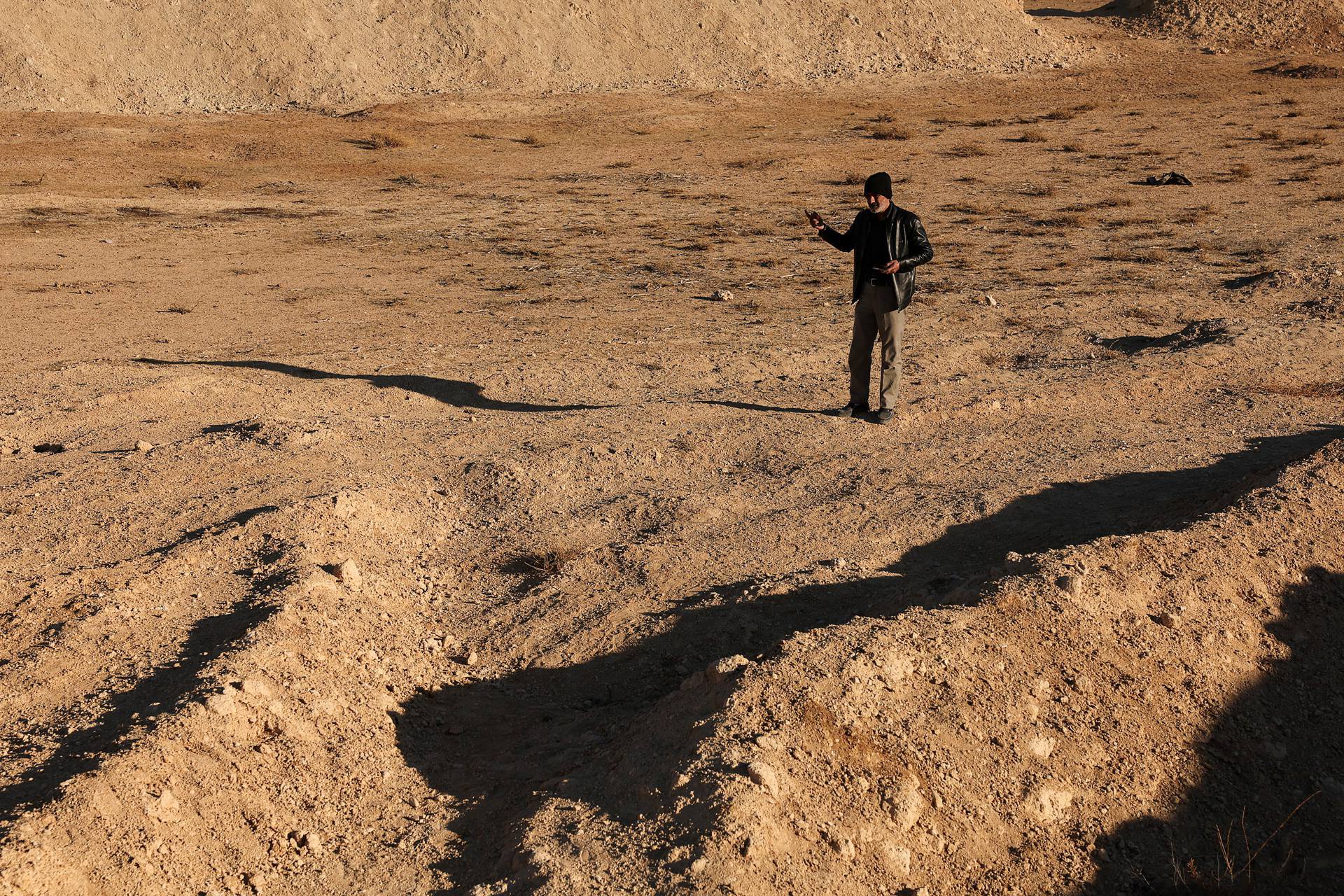 People inspect the site of a mass grave from under the rule of Syria's Bashar al-Assad, in Najha