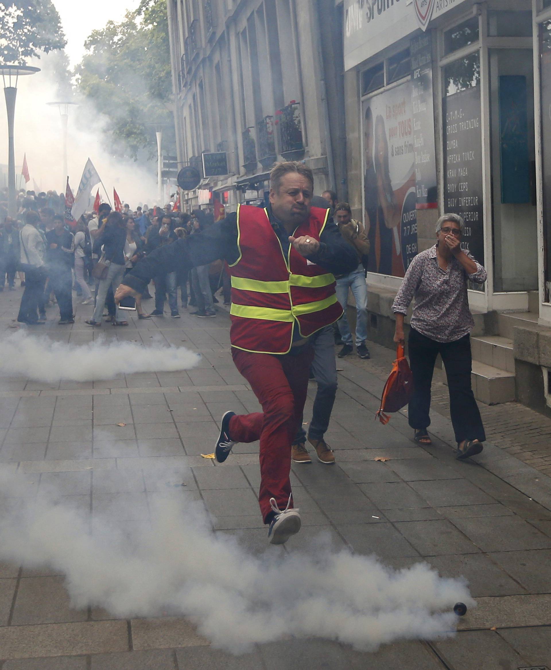 A man runs away from tear gas during clashes with French riot police at a march in Nantes, western France, to demonstrate against the new French labour law