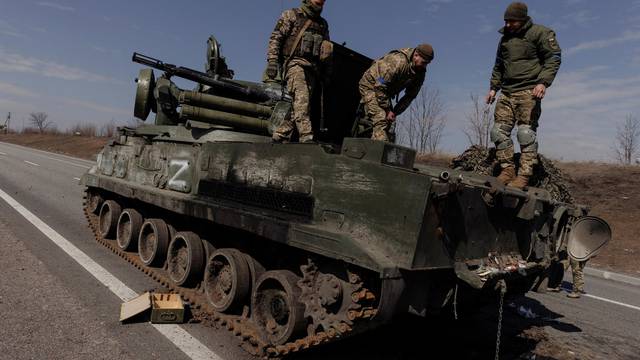 Ukrainian soldiers stand on top of a Russian artillery vehicle they captured during fighting outside Kharkiv