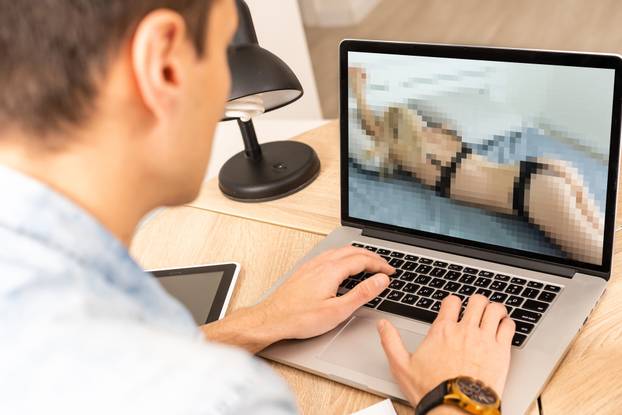 closeup of a young caucasian man watching a nude woman in his computer