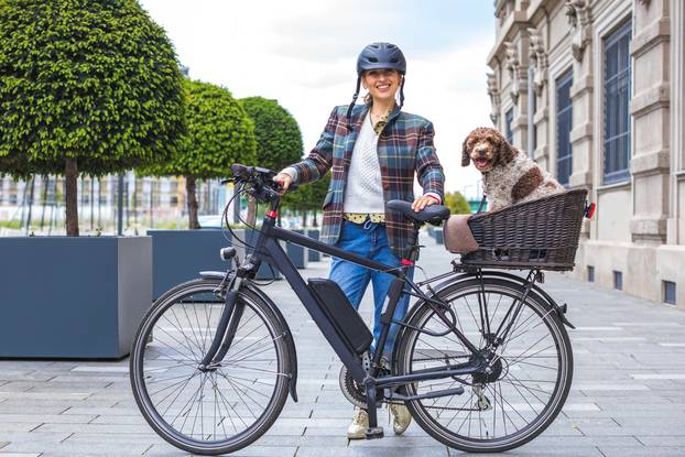 Young,Woman,Pushing,Her,Electric,Bicycle,With,The,Dog,In