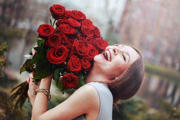 beautiful young woman with a large bouquet of flowers in the park