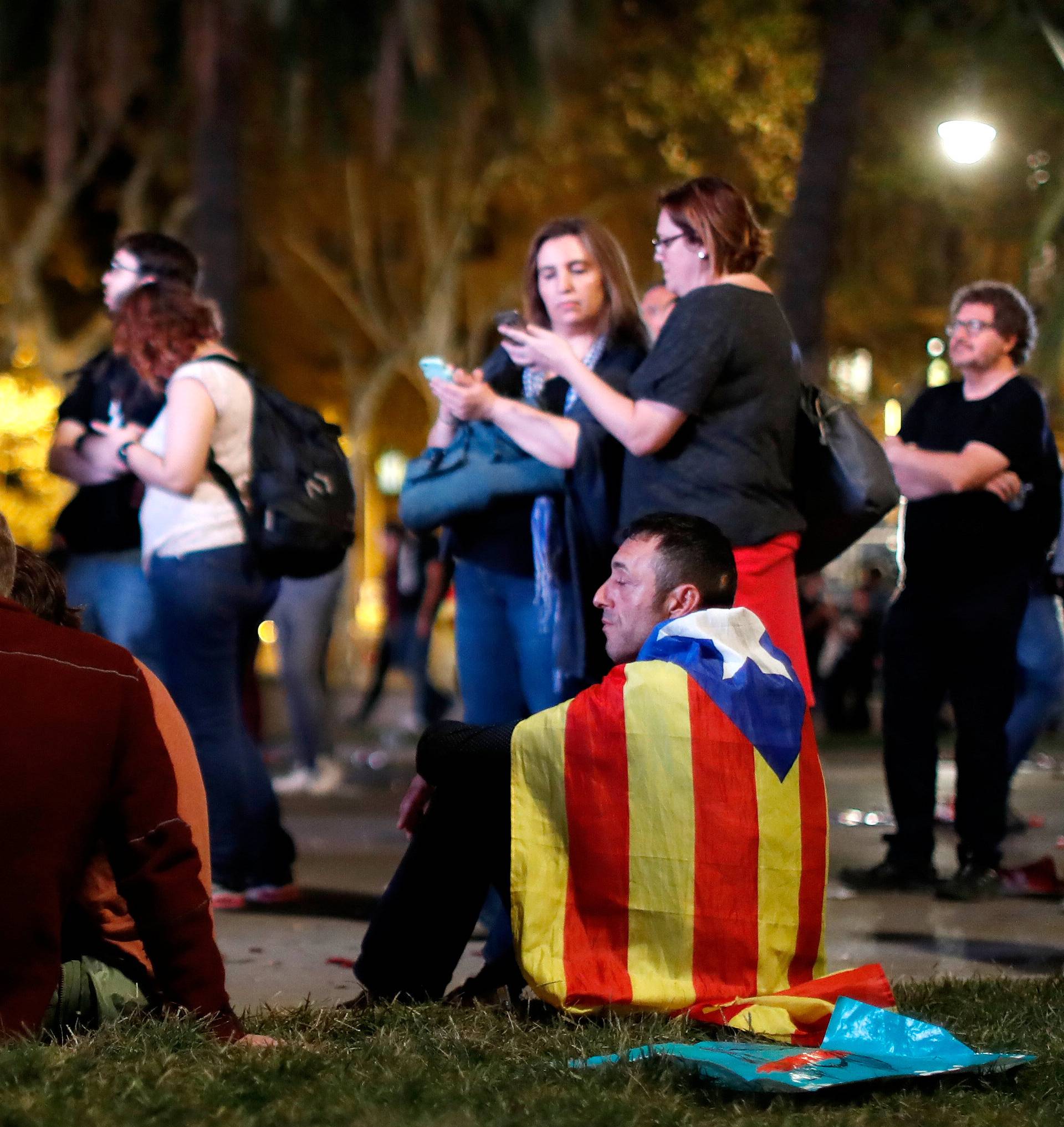 People react as they watch a session of the Catalonian regional parliament on a giant screen at a pro-independence rally in Barcelona