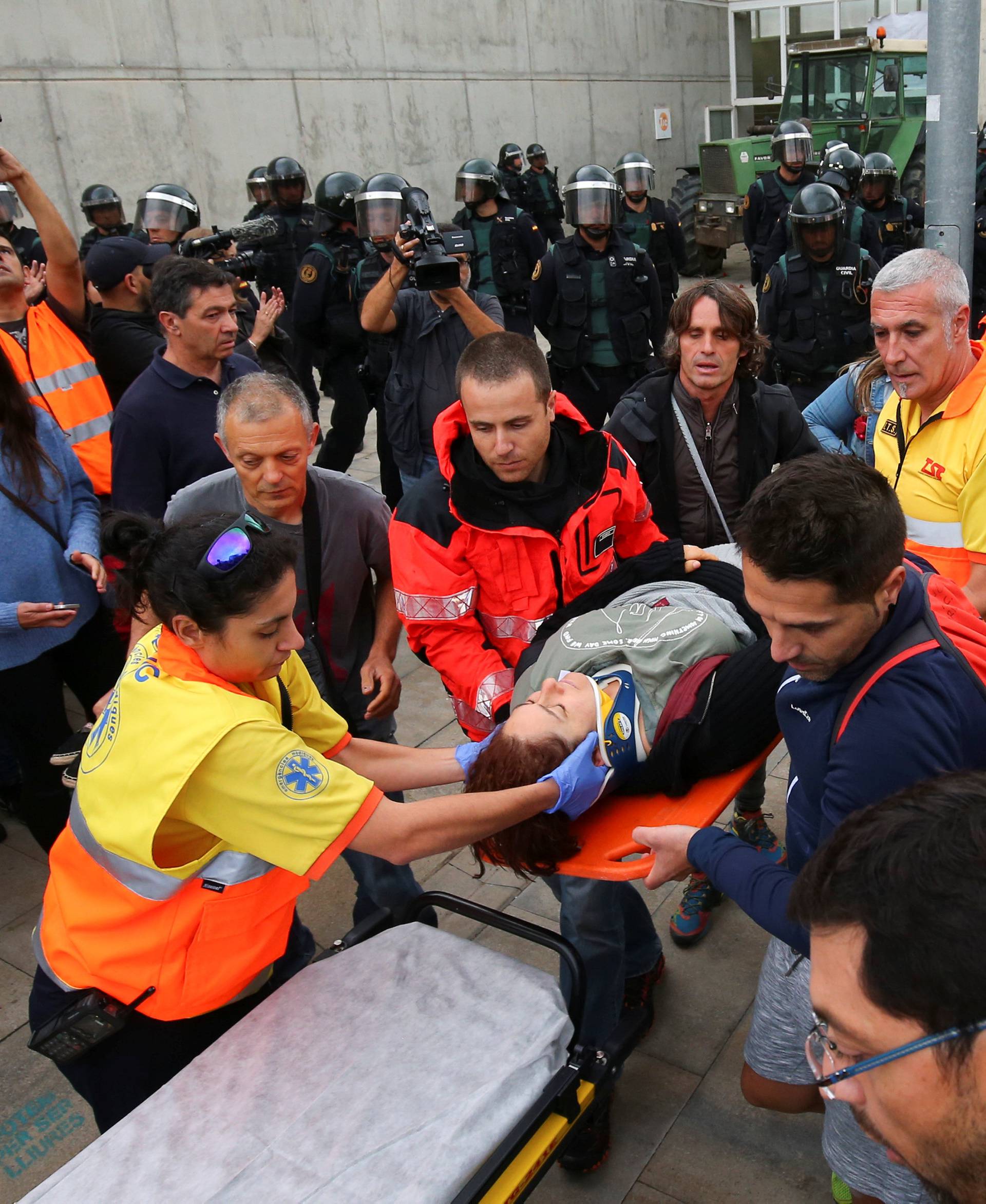 Woman is carried onto stretcher by ambulance crew outside Catalonia referendum polling station in Sant Julia de Ramis