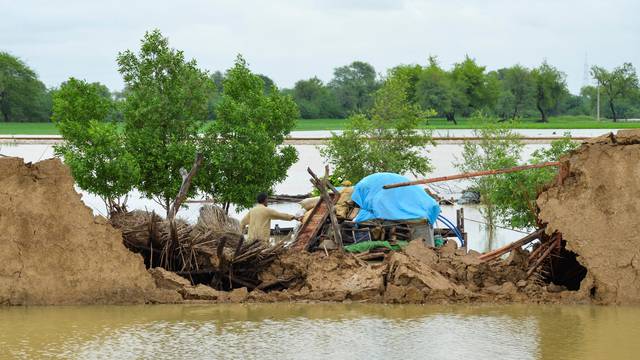 A flood victim retrieves usable items from his damaged house following rains and floods during the monsoon season in Jafarabad