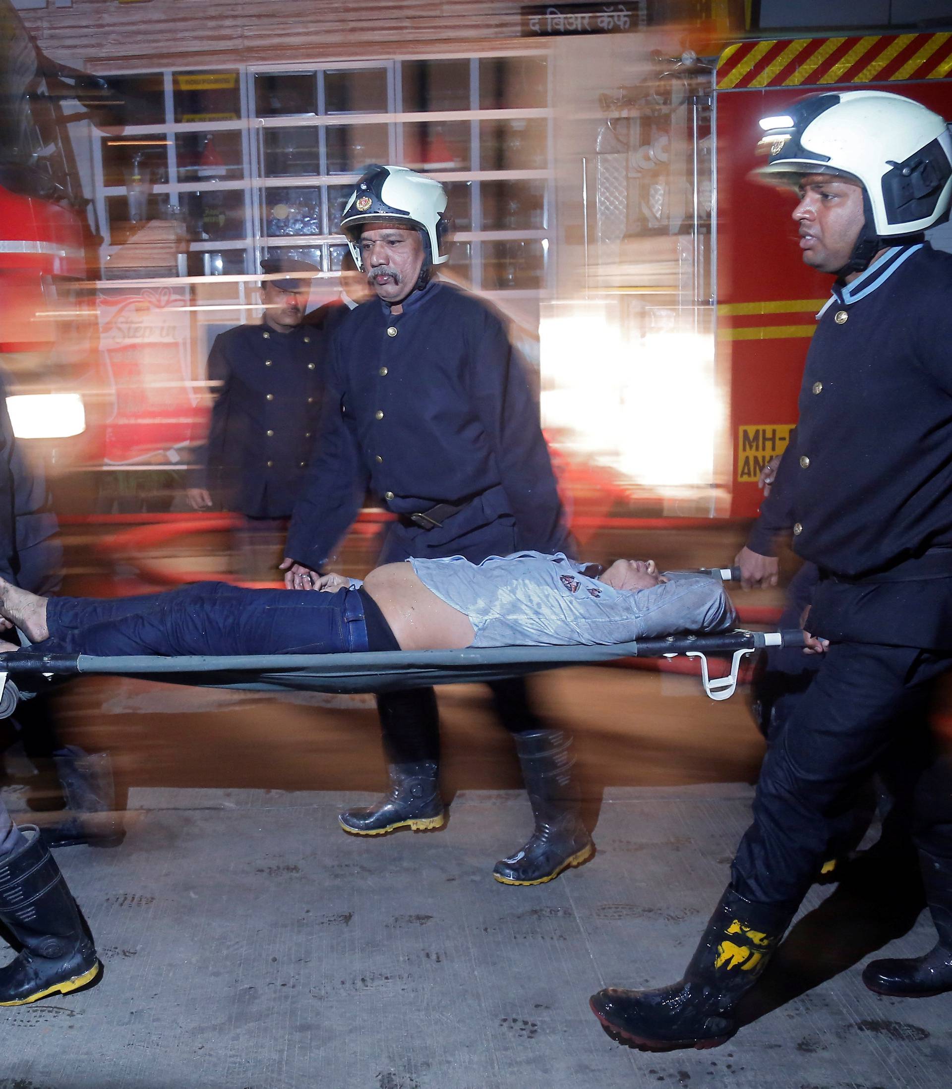 Firefighters carry a victim on a stretcher after a fire at a restaurant in Mumbai