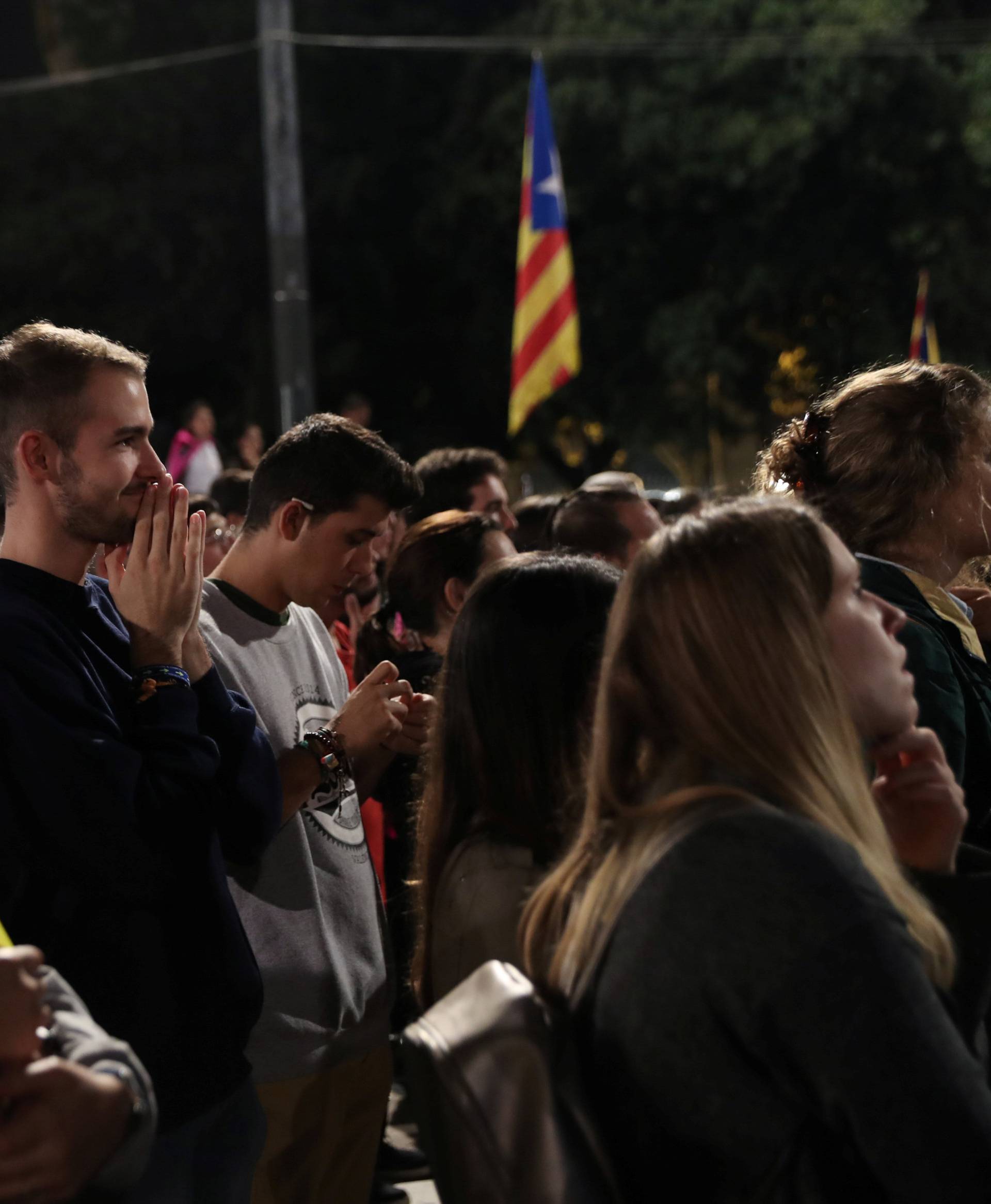 People react as they listen to Catalan president Carles Puigdemont during a gathering at Plaza Catalunya after voting ended for the banned independence referendum, in Barcelona