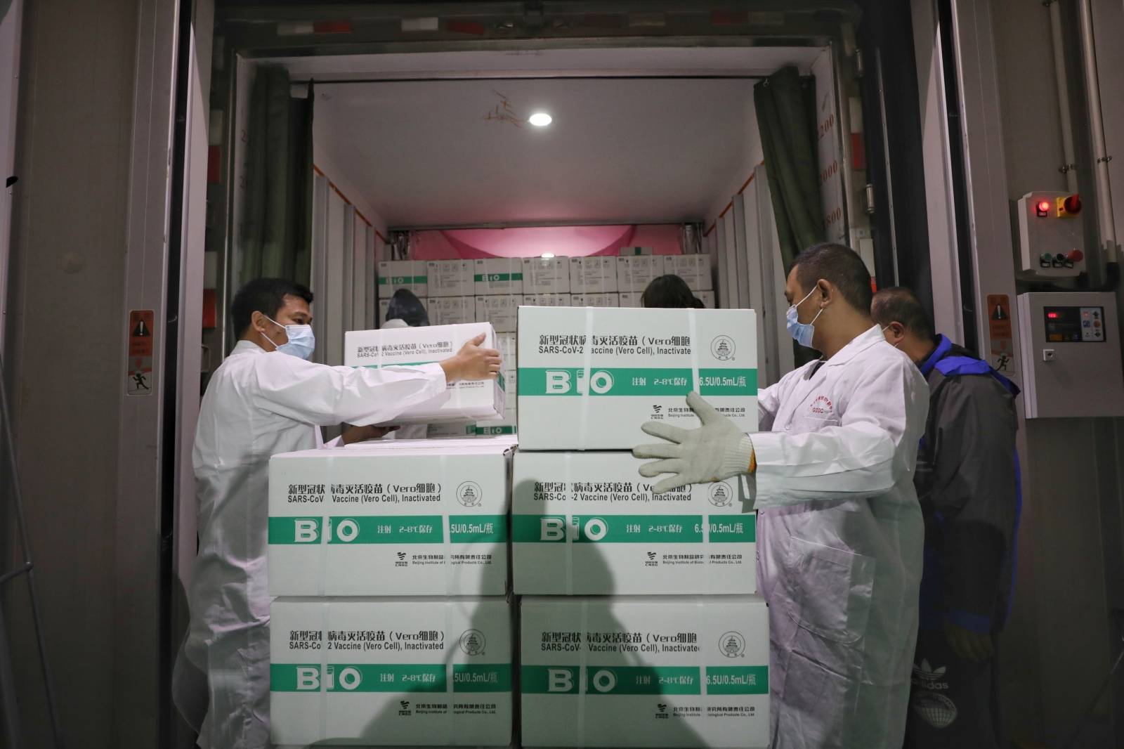 Workers transport boxes of COVID-19 vaccines from a truck to a cold storage facility in Guangzhou