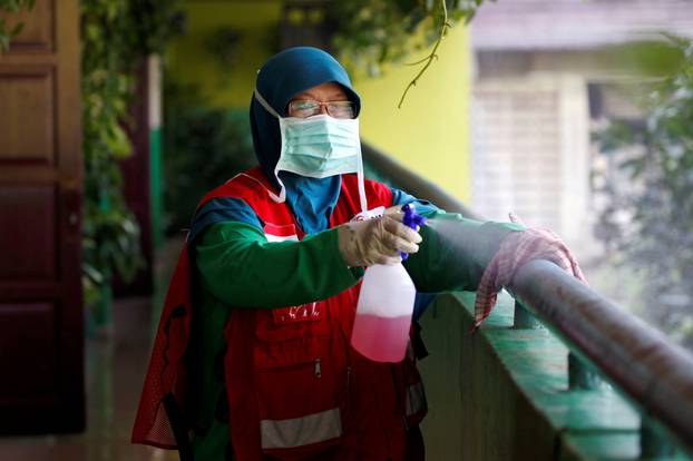 Indonesian Red Cross personnel sprays disinfectant at the corridor of a school closed amid the spread of coronavirus in Jakarta