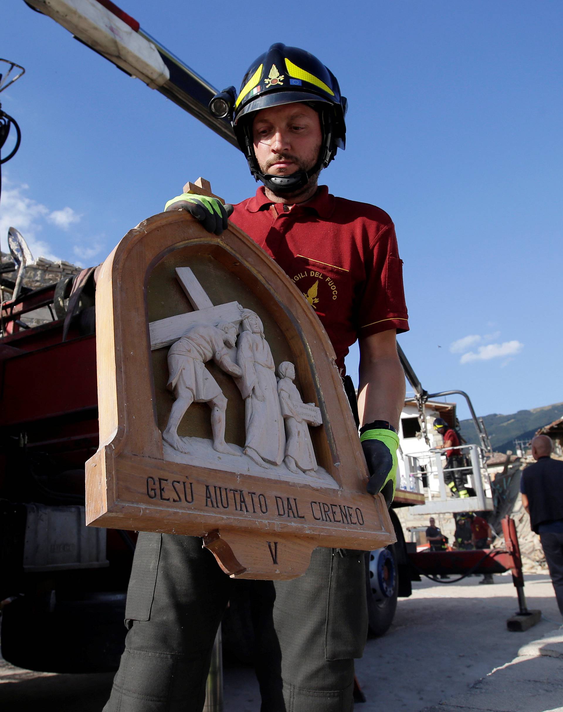 A firefighter carries away a bas-relief from San Lorenzo e Flaviano church following an earthquake in San Lorenzo