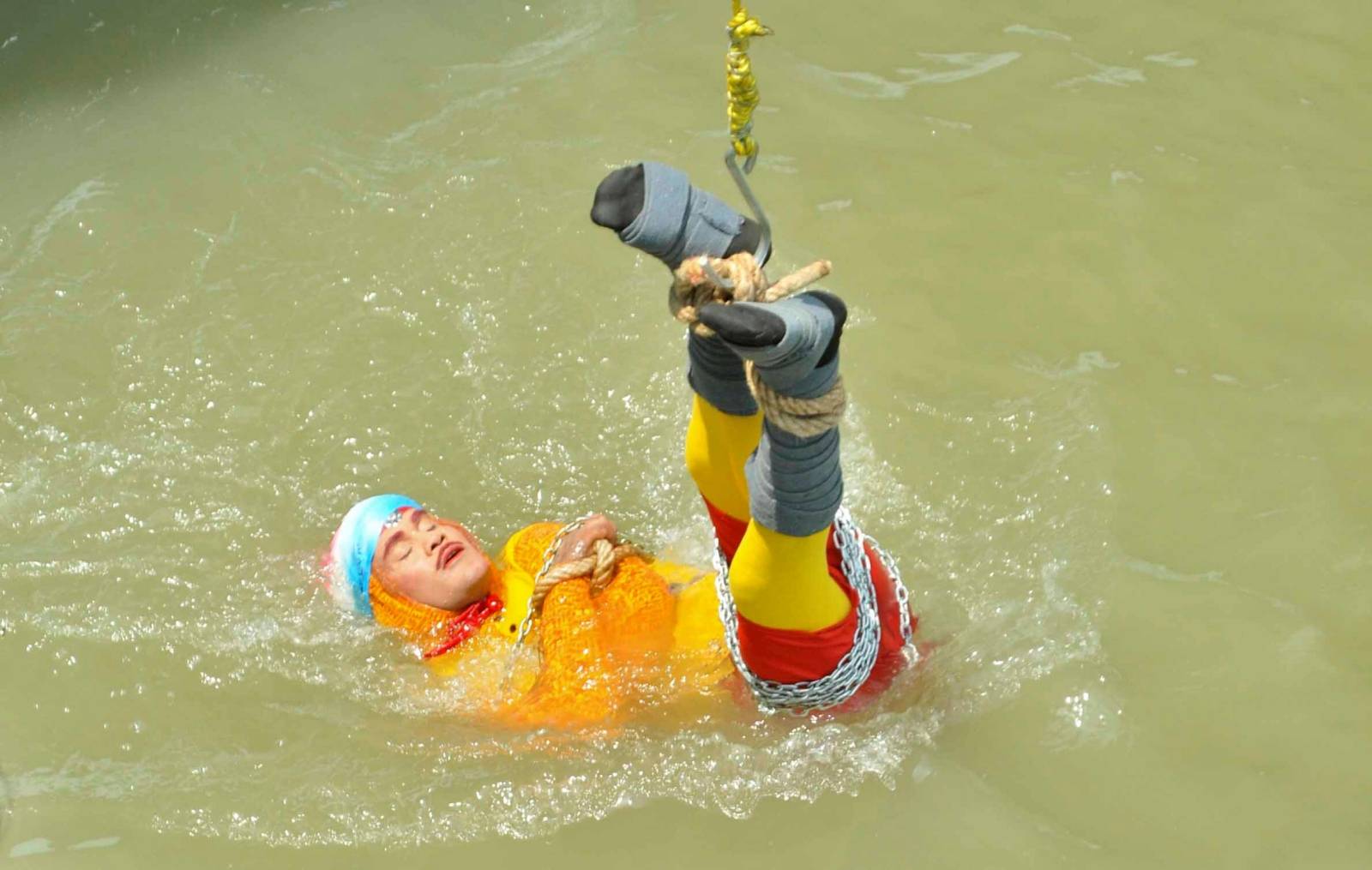 Chanchal Lahiri, a magician, is lowered into the Hooghly river as he performs one of his tricks in Kolkata