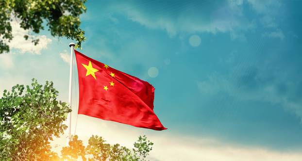 China,National,Flag,Waving,In,The,Sky,Behind,The,Tree.