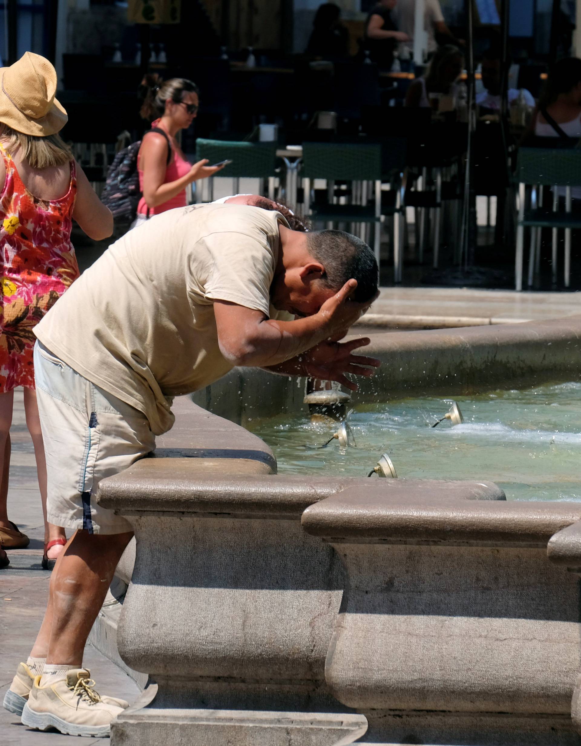 A man cools off at a fountain during the heatwave at the Virgin Square in Valencia