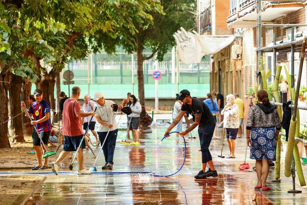 Residents clean a sidewalk in Sant Adria del Besos amid AEMET red alert for Catalonia
