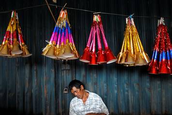 A trader falls asleep as he sells paper trumpets on the streets of Jakarta