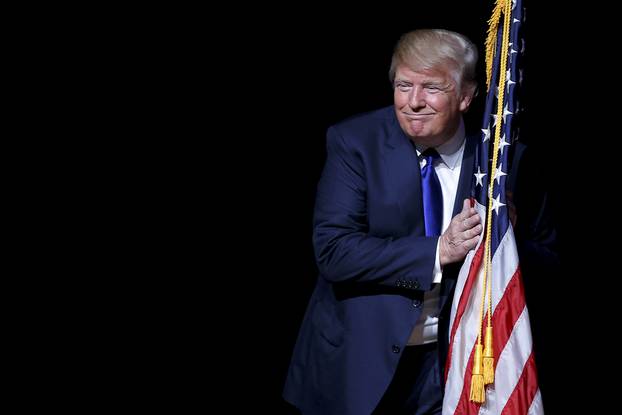 U.S. Republican presidential candidate Trump hugs a U.S. flag as he takes the stage for a campaign town hall meeting in Derry