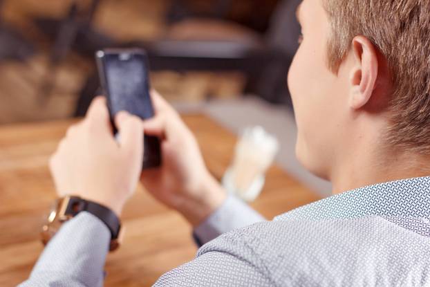 Handsome guy using mobile phone in cafe 