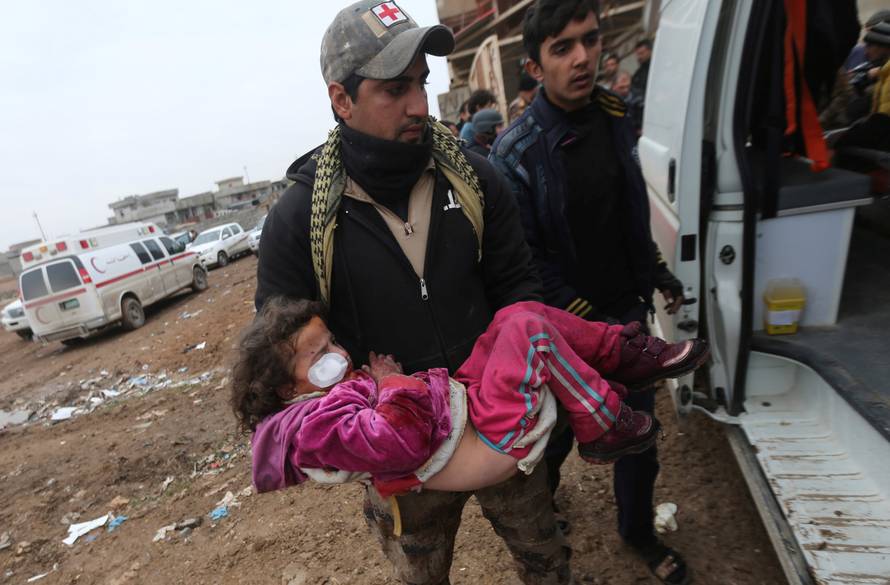 An Iraqi soldier carries a girl who was wounded during clashes in the Islamic State stronghold of Mosul into a field hospital in al-Samah neighborhood Iraq