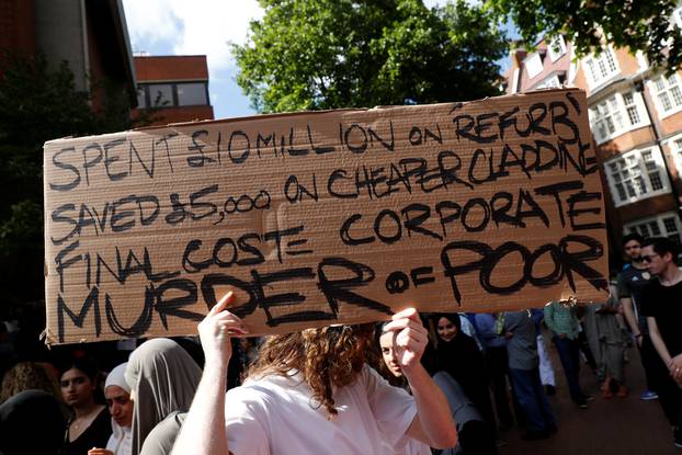 A demonstrator holds a banner during a protest at Kensington Town Hall, following the fire that destroyed The Grenfell Tower block, in north Kensington, West London