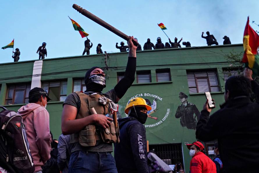 Opponents to Bolivia's President Evo Morales react as police officers stand on the roof of their headquarters, in Cochabamba
