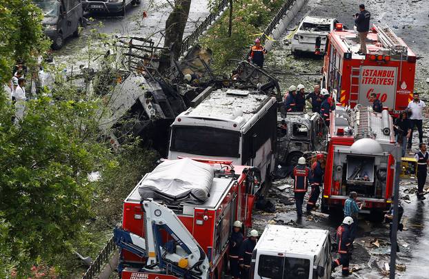 Forensic experts and firefighters stand beside a Turkish police bus which was targeted in a bomb attack in Istanbul