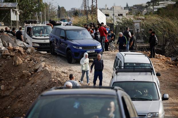 Displaced people cross the bridge linking southern Lebanon to the rest of the country, which was hit earlier in an Israeli strike, in Qasmiyeh