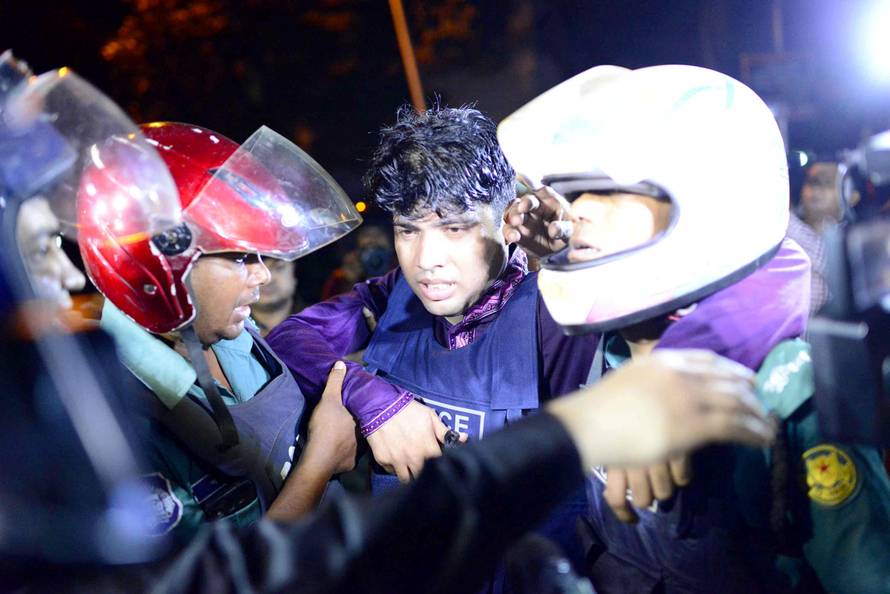 An injured member of the police personnel is carried away by his colleagues after gunmen stormed a restaurant popular with expatriates in the diplomatic quarter of Dhaka