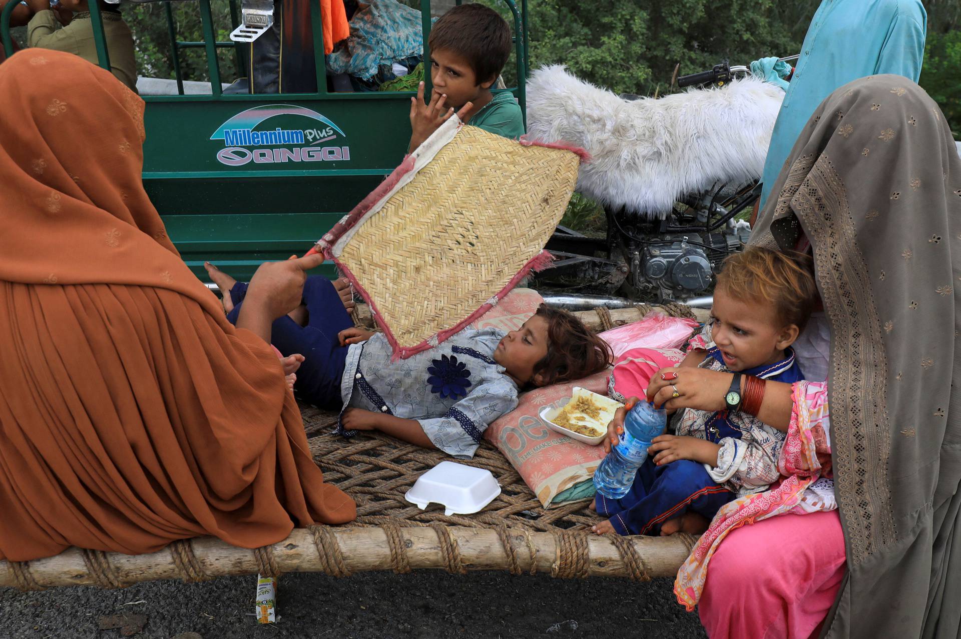 Women and children sit outside their tent, after taking refuge on a motorway, following rains and floods during the monsoon season in Charsadda