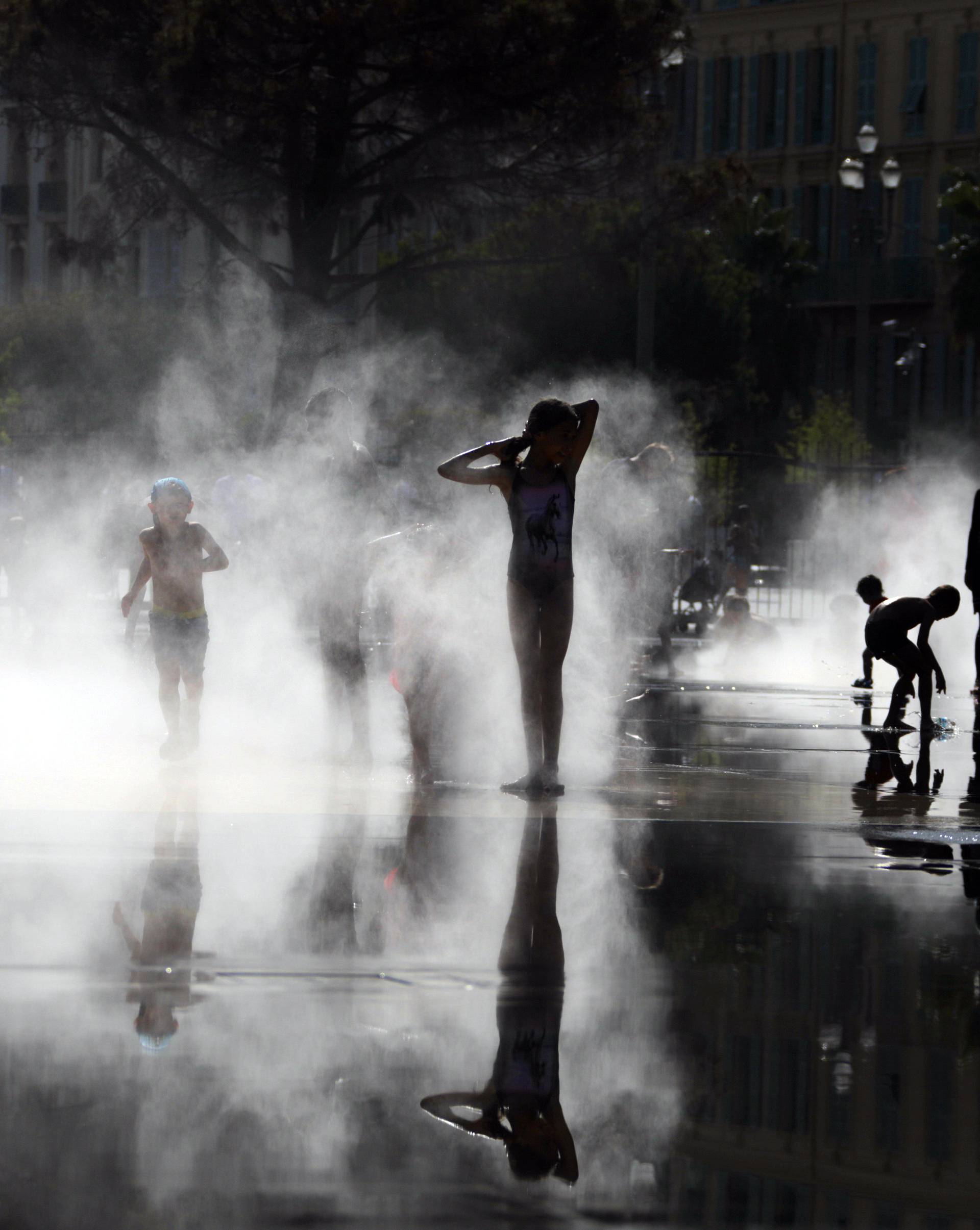 Children play in mist at a water fountain as a heatwave hits south of France in Nice