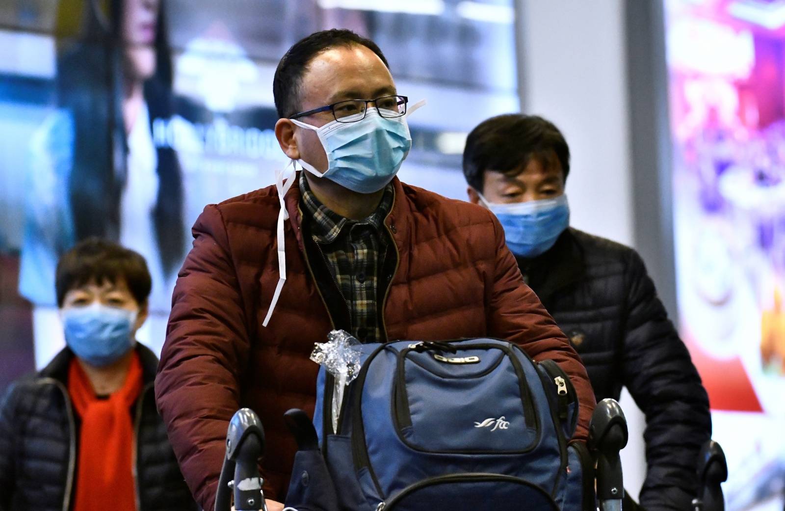 Travellers wearing masks arrive on a direct flight from China at Vancouver International Airport