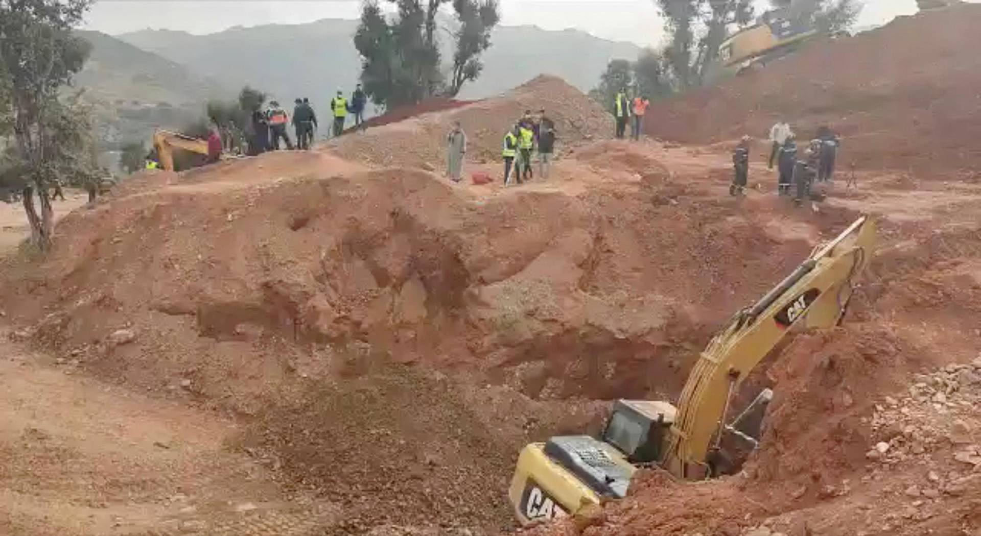 People use machinery to excavate the ground in order to free a boy trapped in an underground well, in Chefchaouen