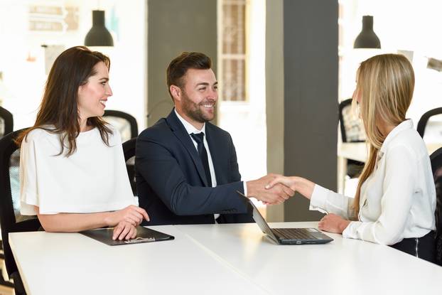 Smiling young couple shaking hands with an insurance agent