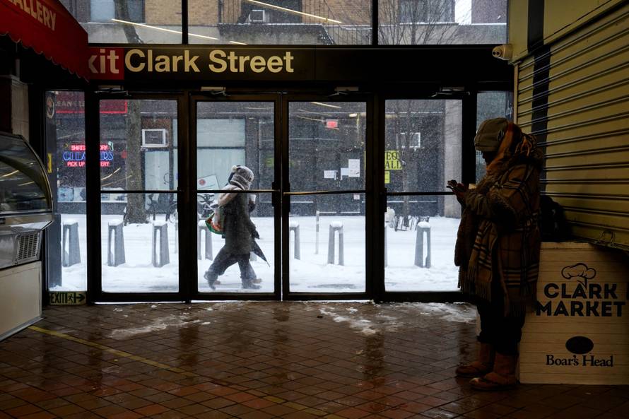 A woman takes shelter inside the entrance to the Clark Street subway station, in Brooklyn