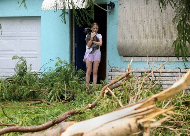Mallory Tollett, 12, comforts her dog Maggie after a suspected tornado went through her family's property