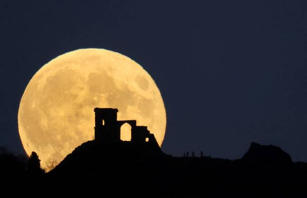 People watch as the Supermoon, known as the Hunter’s moon rises over Mow Cop castle in Mow Cop