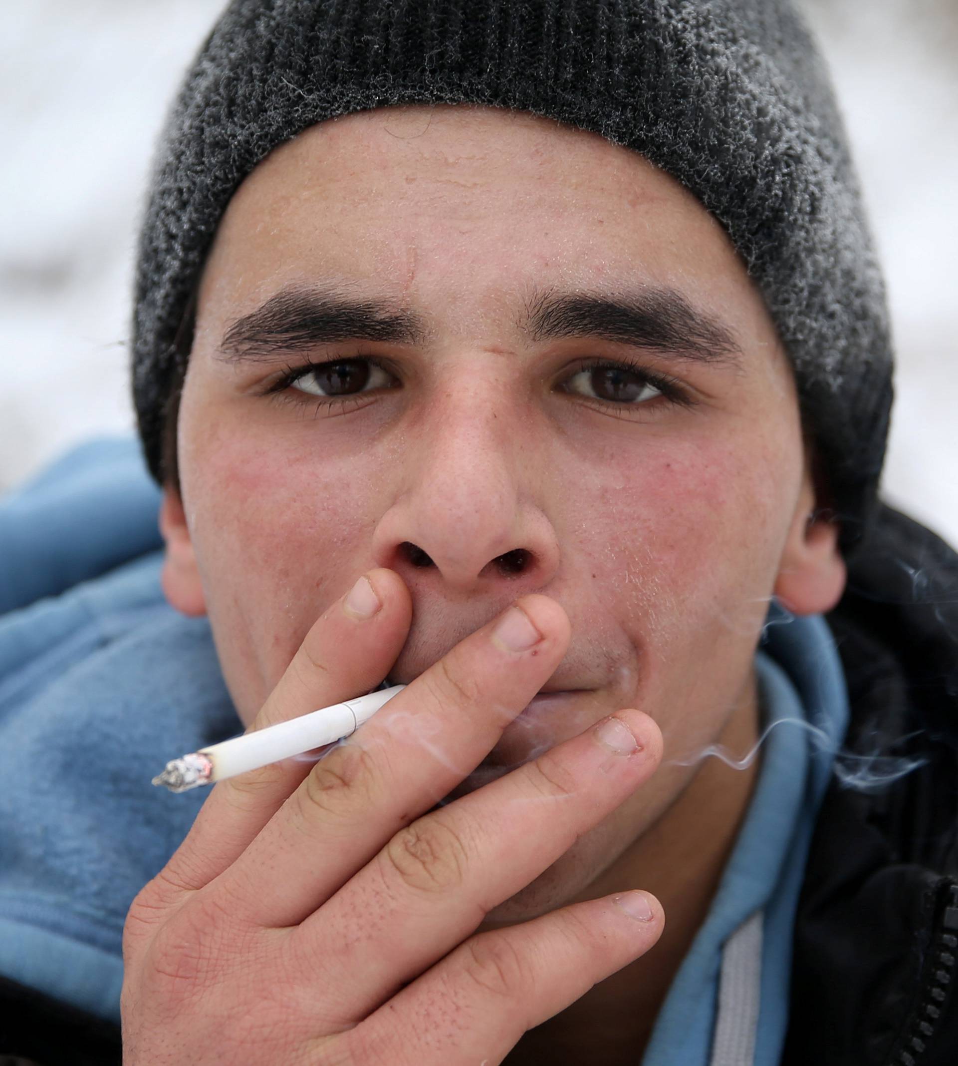 A migrant smokes while attempting to illegally cross the border into Croatia on the Pljesevica Mountain near Bihac